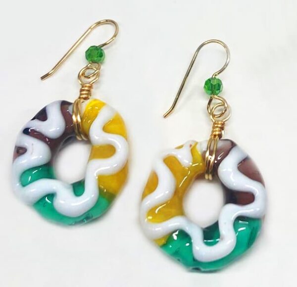 Purple, Green and Yellow glass earrings shaped like a Mardi Gras King Cake with white icing on top