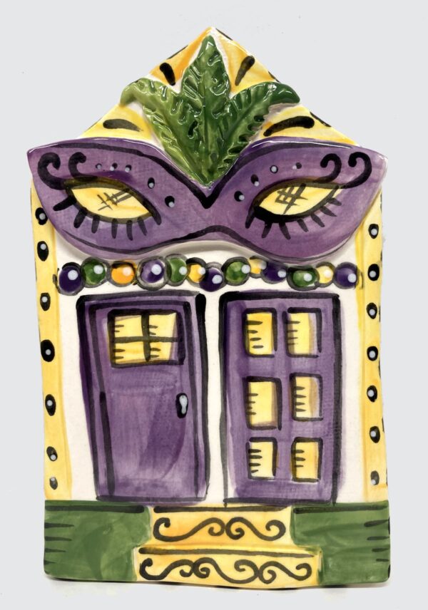 Ceramic plaque as a house decorated for Mardi Gras with large purple mask.